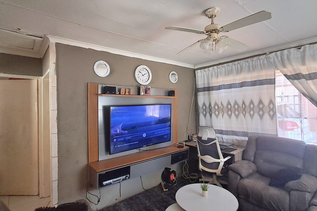 Living room featuring a built-in media console and ceiling fan, requiring cosmetic updates to the ceiling and wall finishes.