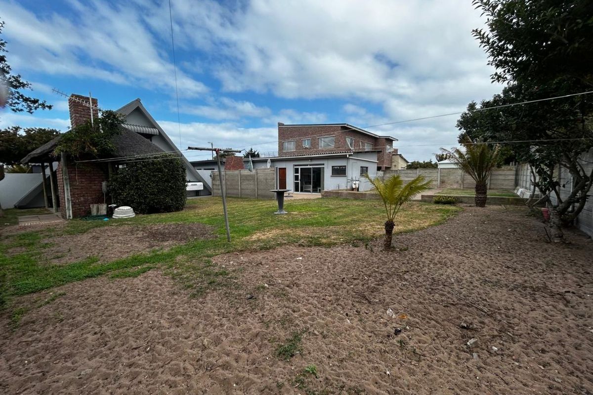 Spacious rear garden featuring a lawn area, established trees, and a brick-built outdoor structure, providing a private outdoor space for the property.