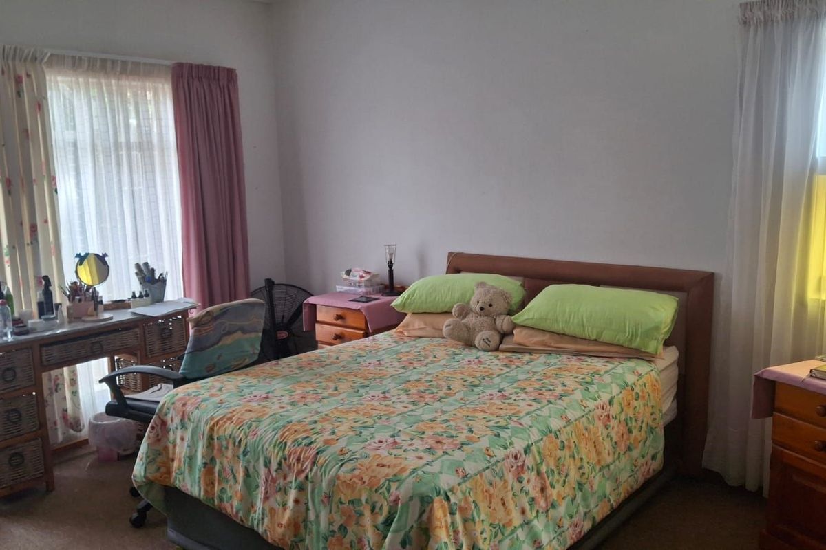 A bedroom featuring dual aspect windows with curtains, providing natural light and a functional layout.