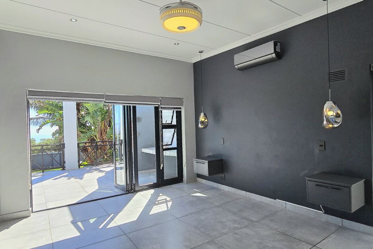 Modern living area featuring large format floor tiles, built-in cabinetry, wall-mounted storage units, and seamless access to an outdoor patio through folding glass doors.