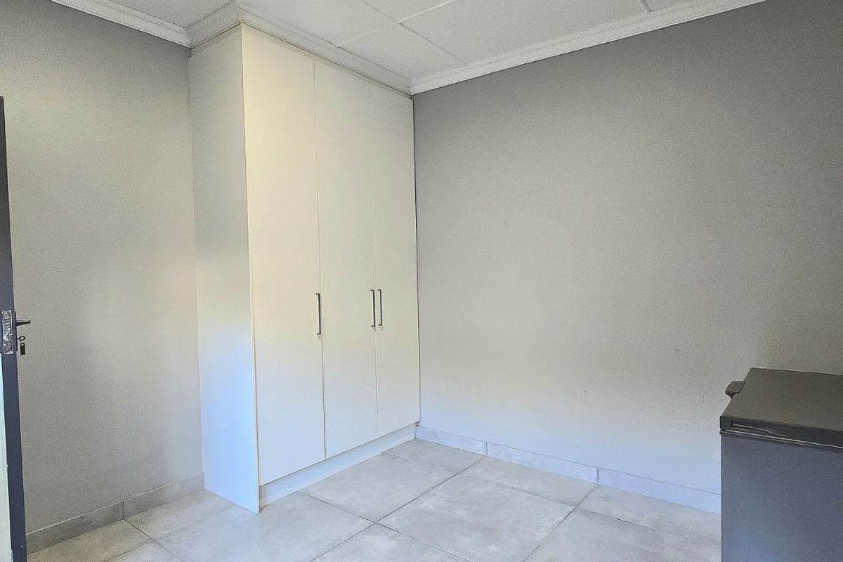 A functional room featuring built-in white cabinetry, tiled flooring, and neutral wall finishes, offering versatile space for storage or utility use.