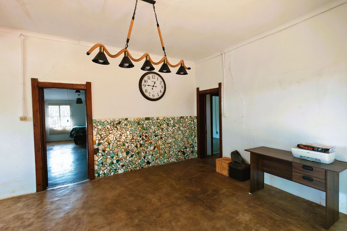 Interior living space featuring a unique mosaic tile wall accent, exposed concrete flooring, and dual doorways leading to adjacent rooms.