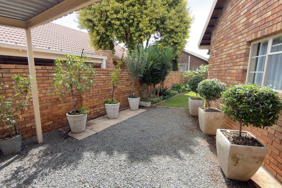 A private rear courtyard featuring a gravel surface, brick boundary walls, and a covered patio area.