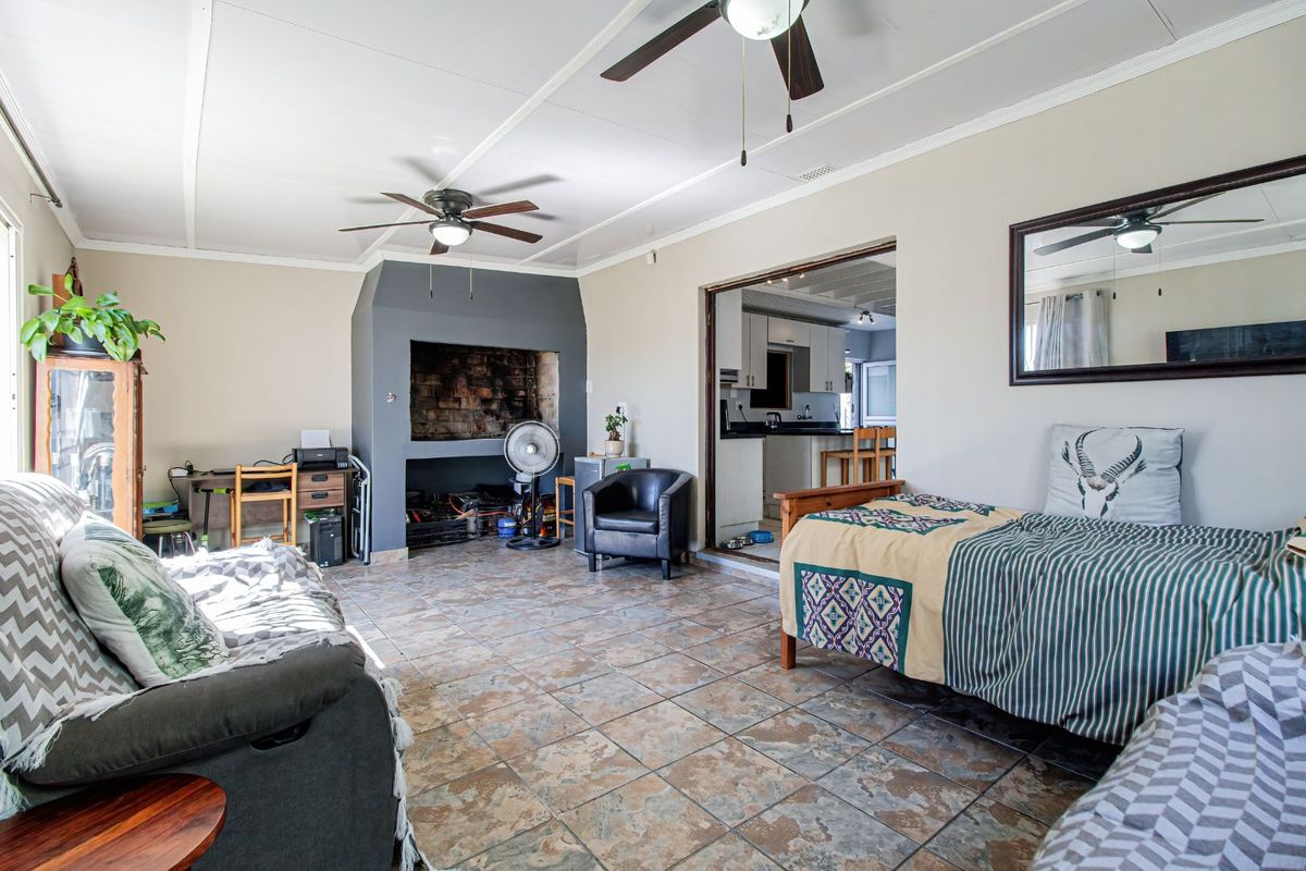 Spacious living area featuring tiled flooring, a built-in fireplace, and ceiling fans, with an open transition into the adjacent kitchen space.
