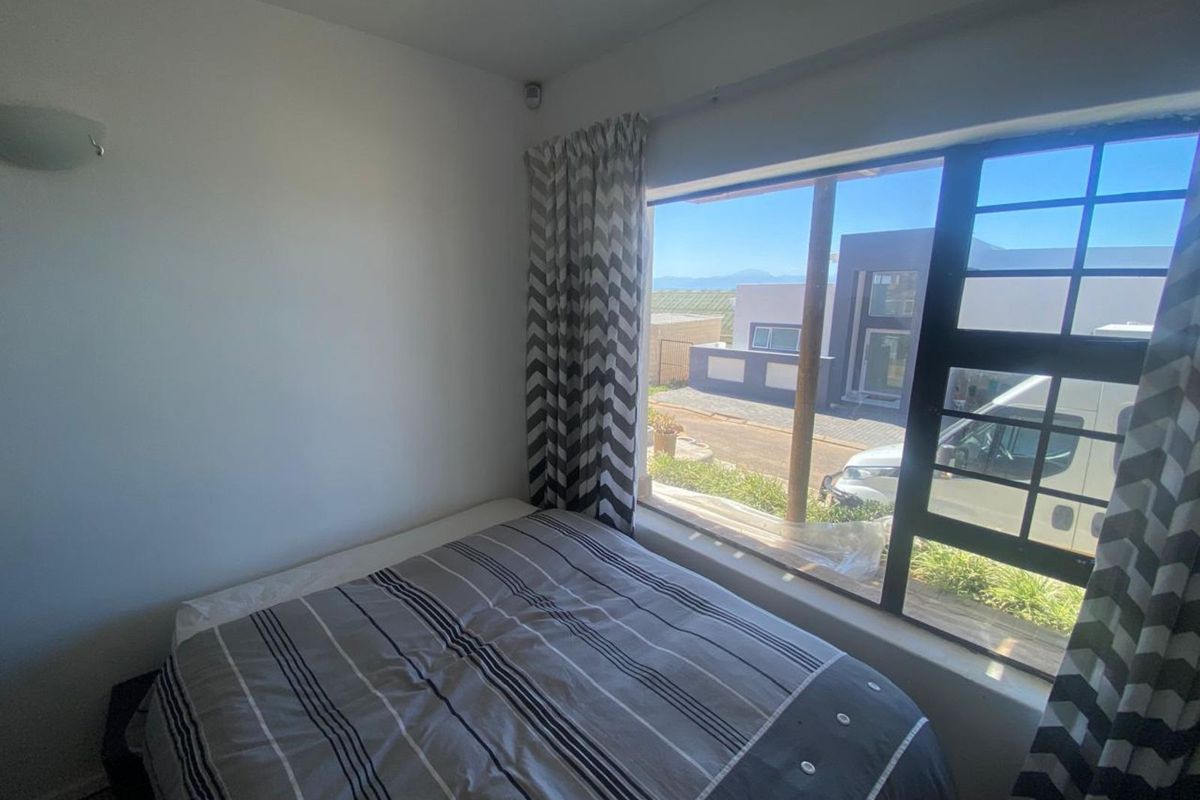 A bedroom featuring a large window with views of the street and neighbouring properties, providing natural light.