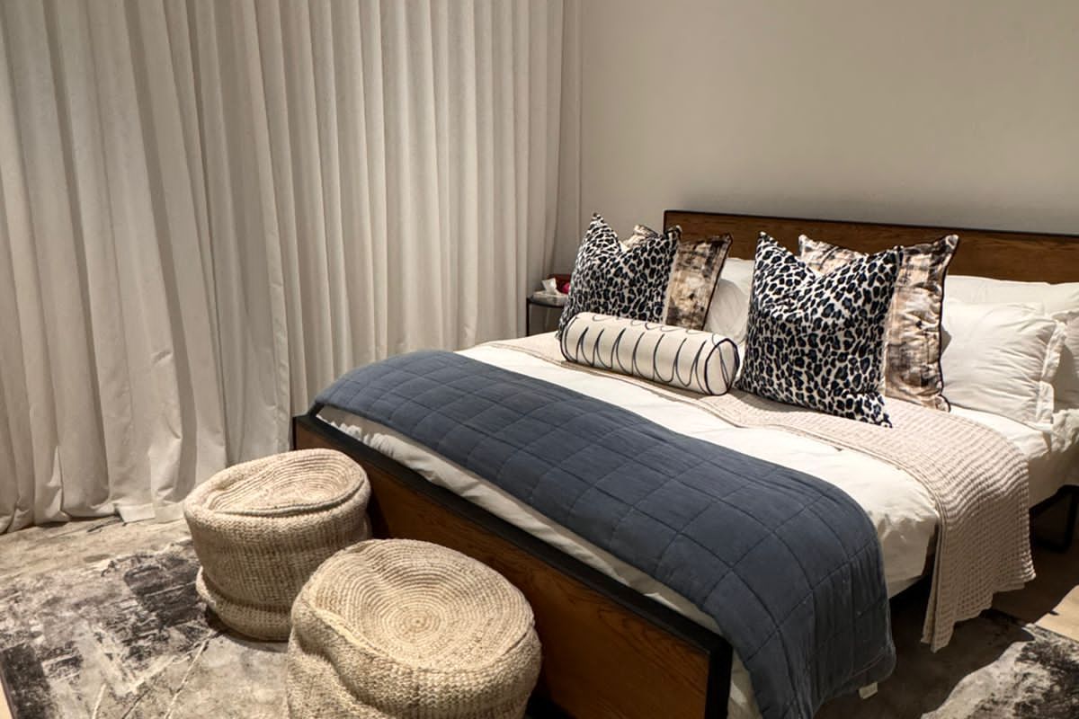 A well-maintained bedroom featuring a wall-mounted air conditioning unit, floor-to-ceiling curtains, and neutral finishes.