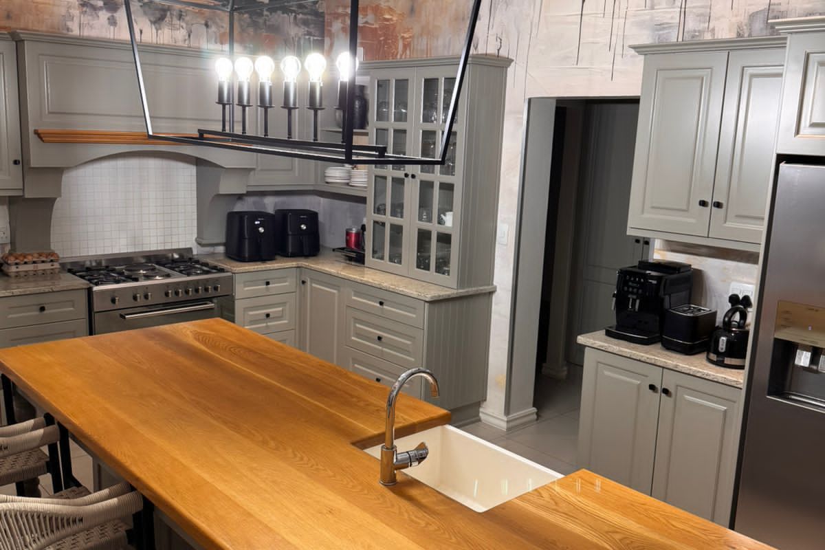 A well-appointed kitchen featuring custom cabinetry, a large wooden island with an integrated sink, and a professional-style gas range.