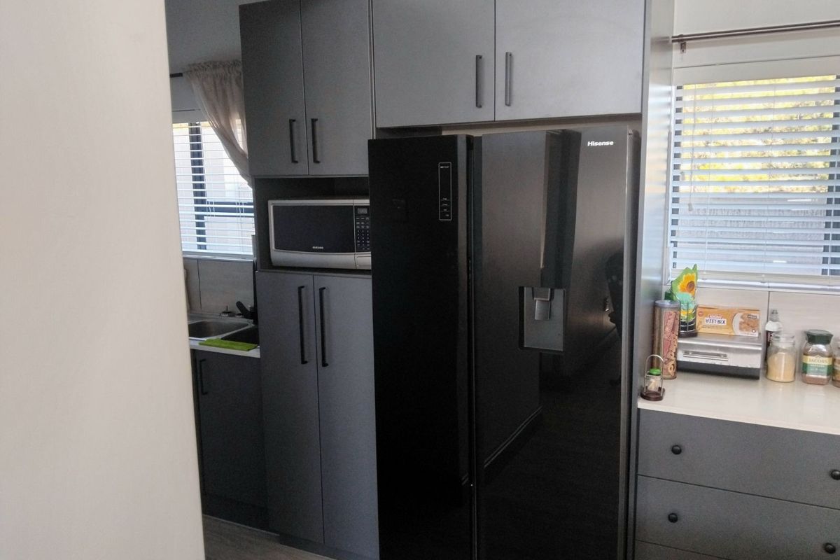 Modern kitchen featuring dark grey cabinetry, integrated microwave, and light-colored countertops, offering a sleek and functional culinary space.