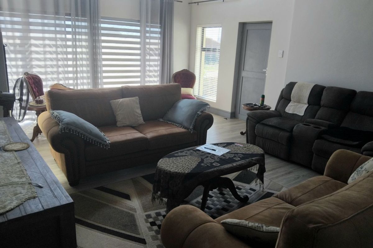 A spacious living room featuring light-toned wood-look flooring, large windows with modern blinds, and neutral wall finishes.