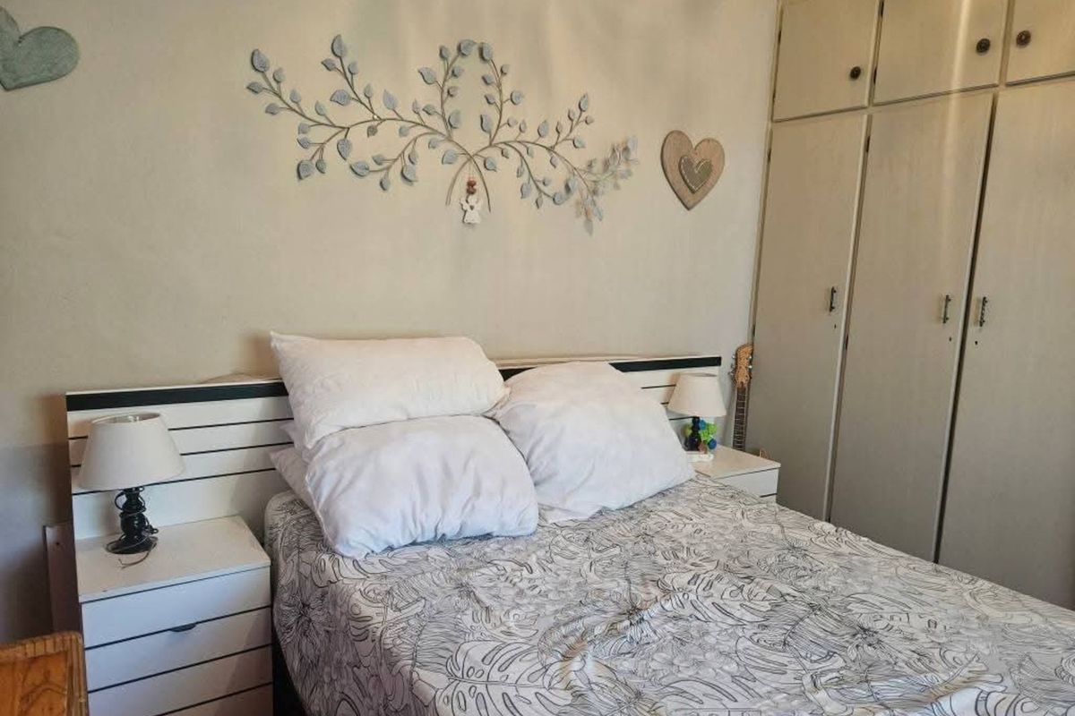 A bedroom featuring built-in floor-to-ceiling wardrobes and a integrated headboard with bedside storage units.
