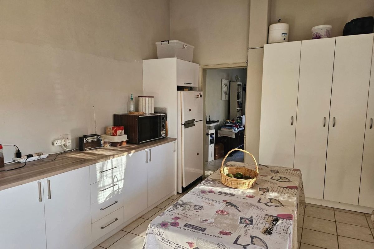 A functional kitchen area featuring white cabinetry, wood-look countertops, and tiled flooring, providing practical storage and workspace.