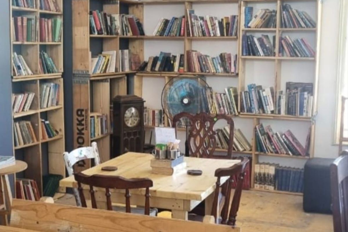 A cozy interior space featuring extensive built-in wooden shelving units, high ceilings, and a neutral color palette suitable for a library or study area.