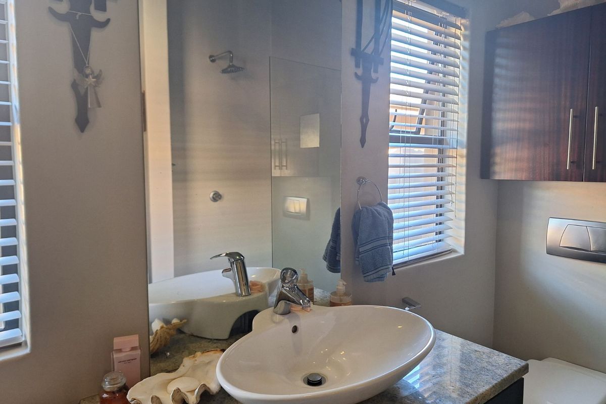 Modern bathroom featuring a granite vanity top, vessel sink, wall-mounted toilet, and a glass-enclosed shower area with a rainfall showerhead.