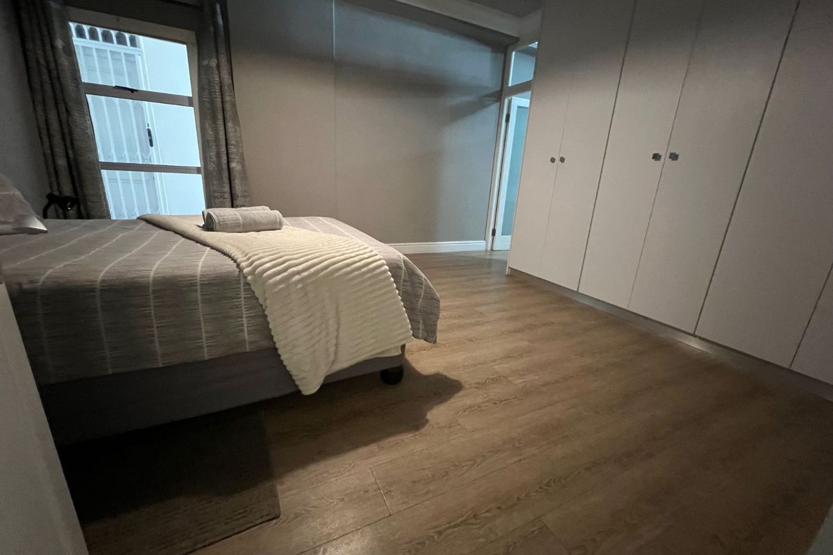 A well-maintained bedroom featuring wood-look laminate flooring and extensive built-in floor-to-ceiling cabinetry for ample storage.