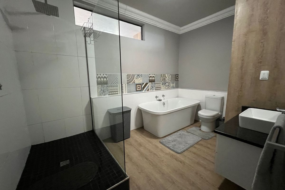 Modern bathroom featuring a walk-in shower with glass enclosure, a freestanding bathtub, a vanity with a vessel sink, and decorative wall tiling.