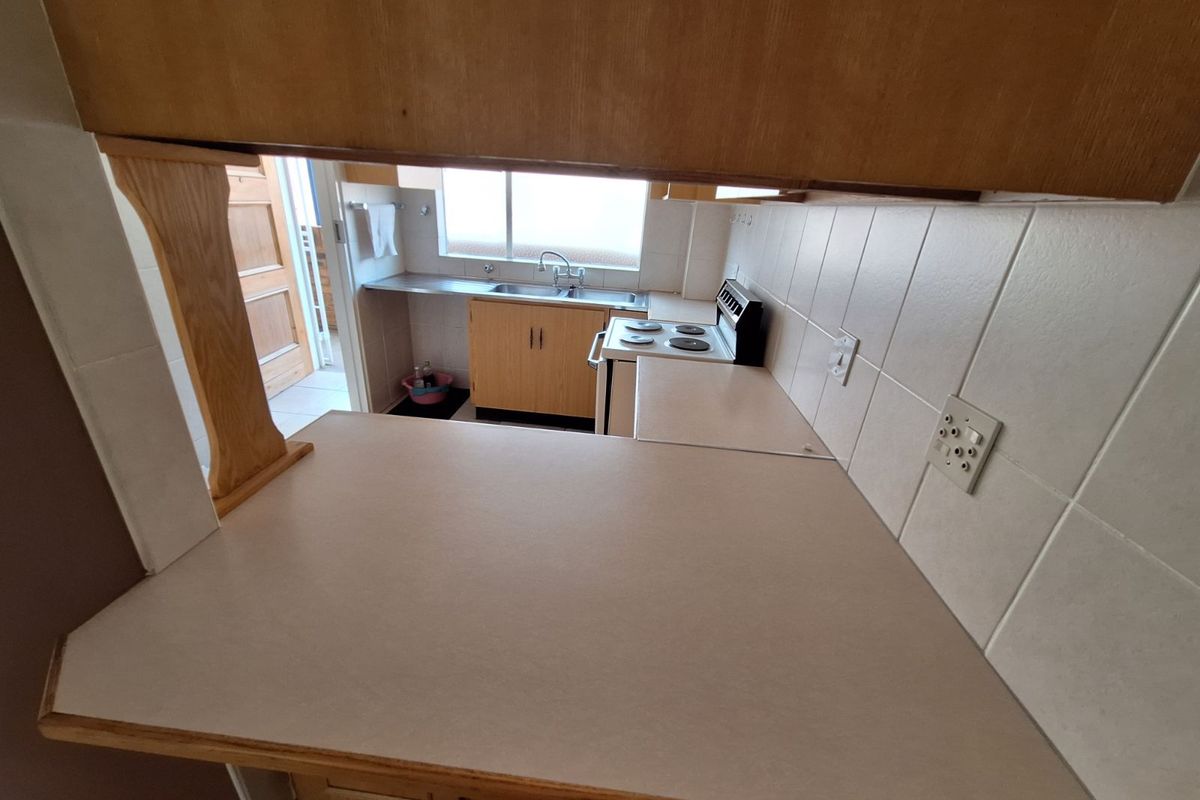A functional kitchen featuring light wood cabinetry, tiled splashbacks, and a built-in electric stove, offering a practical layout for daily meal preparation.