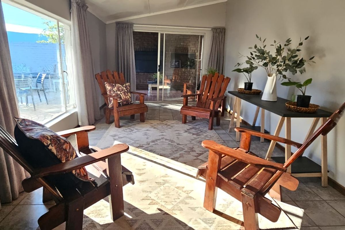 A bright living room featuring large windows, tiled flooring, and sliding glass doors that provide direct access to an outdoor patio area.
