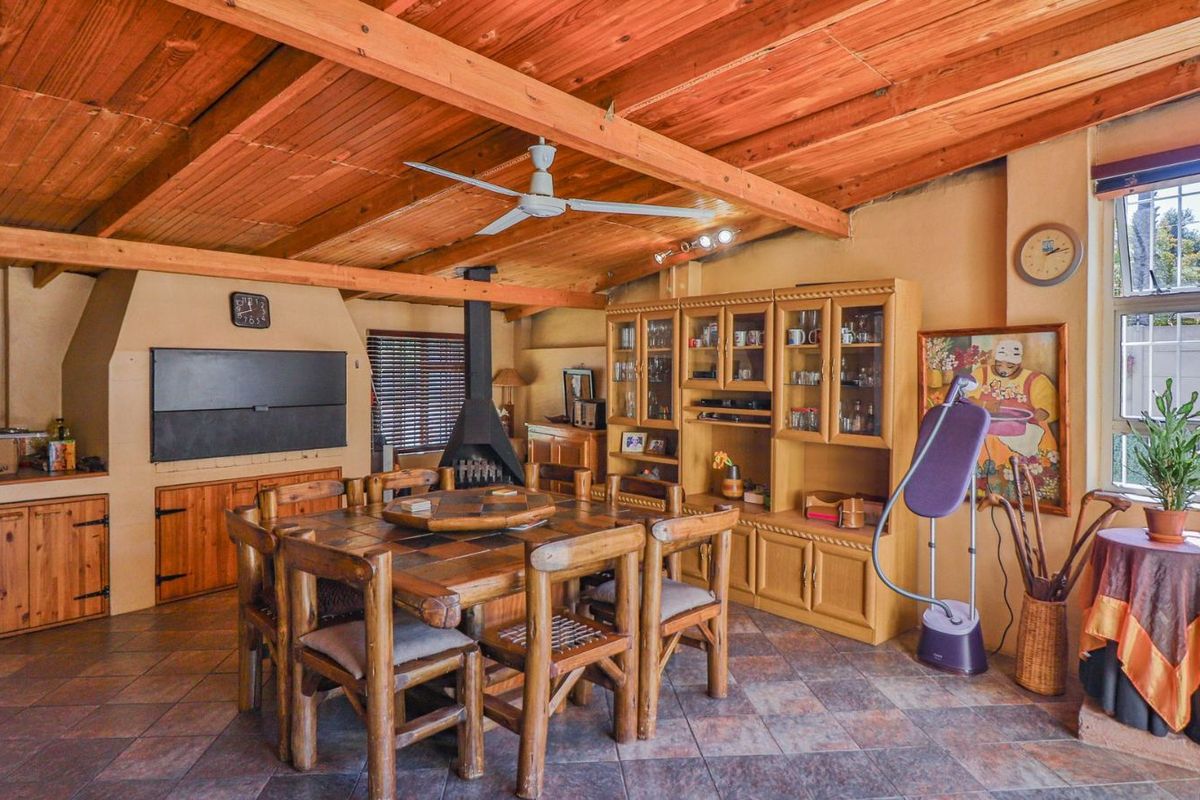 Spacious living area featuring a rustic timber-beamed ceiling, tiled flooring, and a built-in fireplace, creating a warm and traditional atmosphere.