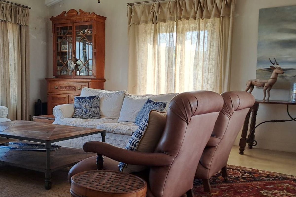 A comfortable living room featuring large windows, neutral flooring, and ample natural light, creating a warm and inviting atmosphere.