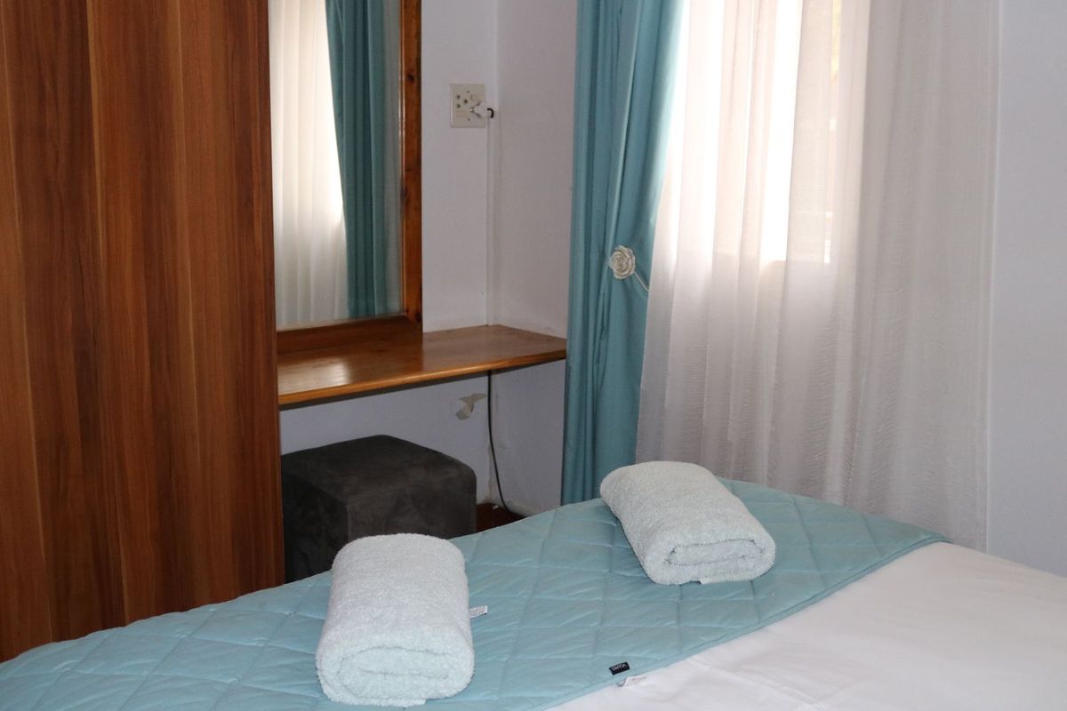 A bedroom featuring a built-in wooden vanity unit with a mirror and a window with curtains.