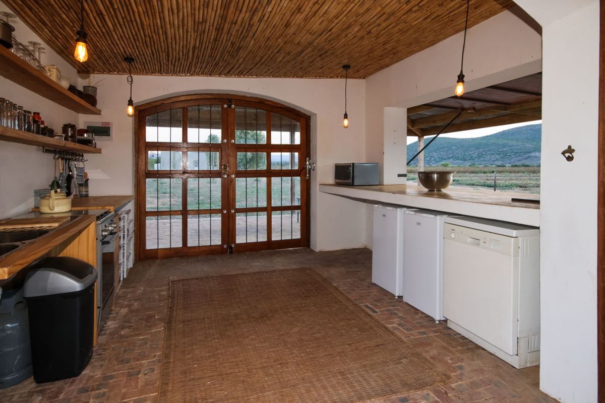 Rustic kitchen area featuring a unique bamboo ceiling, brick flooring, wooden arched double doors, and a built-in counter with integrated appliance space.