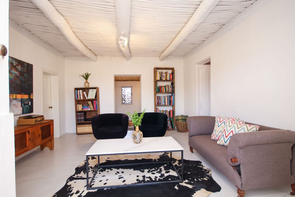 A bright living room featuring a traditional white-painted exposed beam ceiling and smooth flooring, creating a clean and rustic atmosphere.
