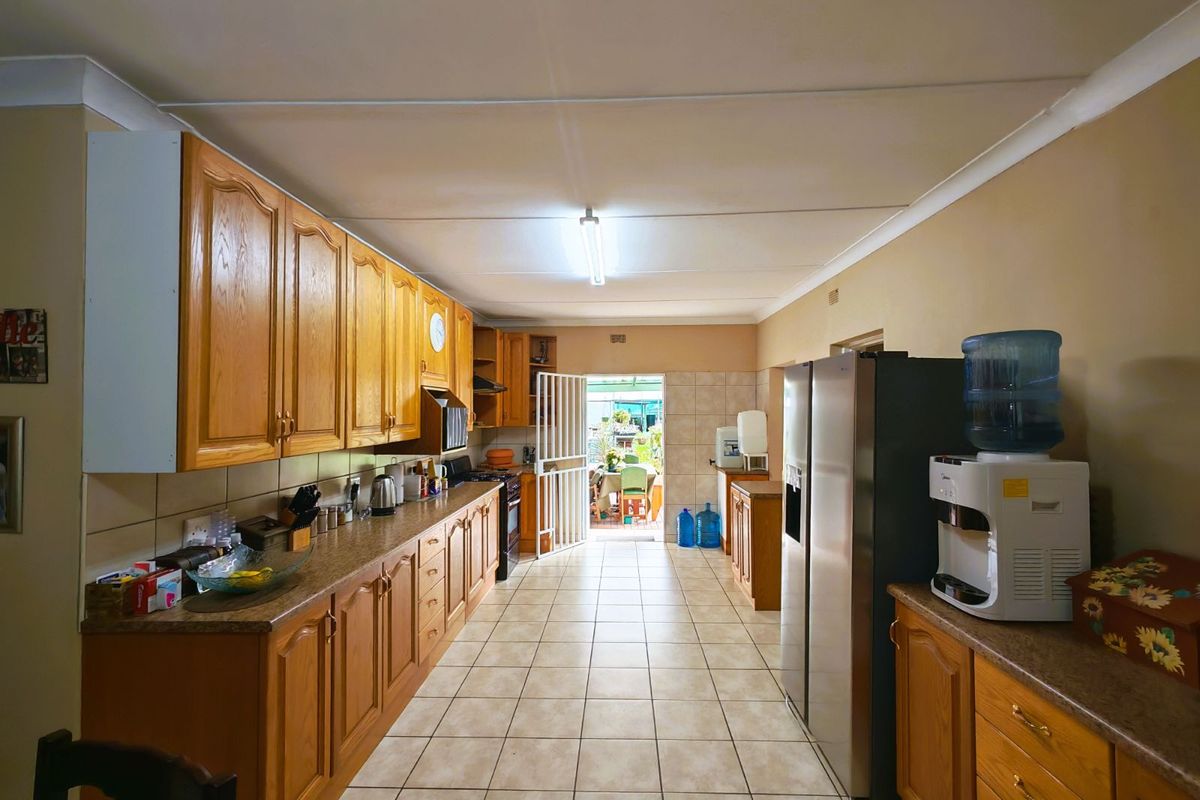Spacious kitchen featuring traditional timber cabinetry, tiled flooring, and direct access to the rear outdoor area.