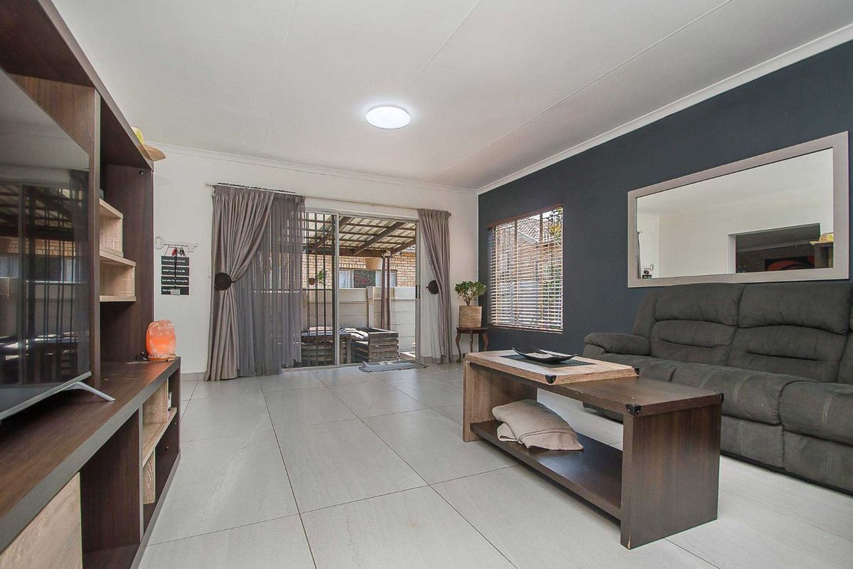 Spacious living room featuring large format floor tiles, a feature accent wall, and sliding glass doors providing access to the outdoor patio area.