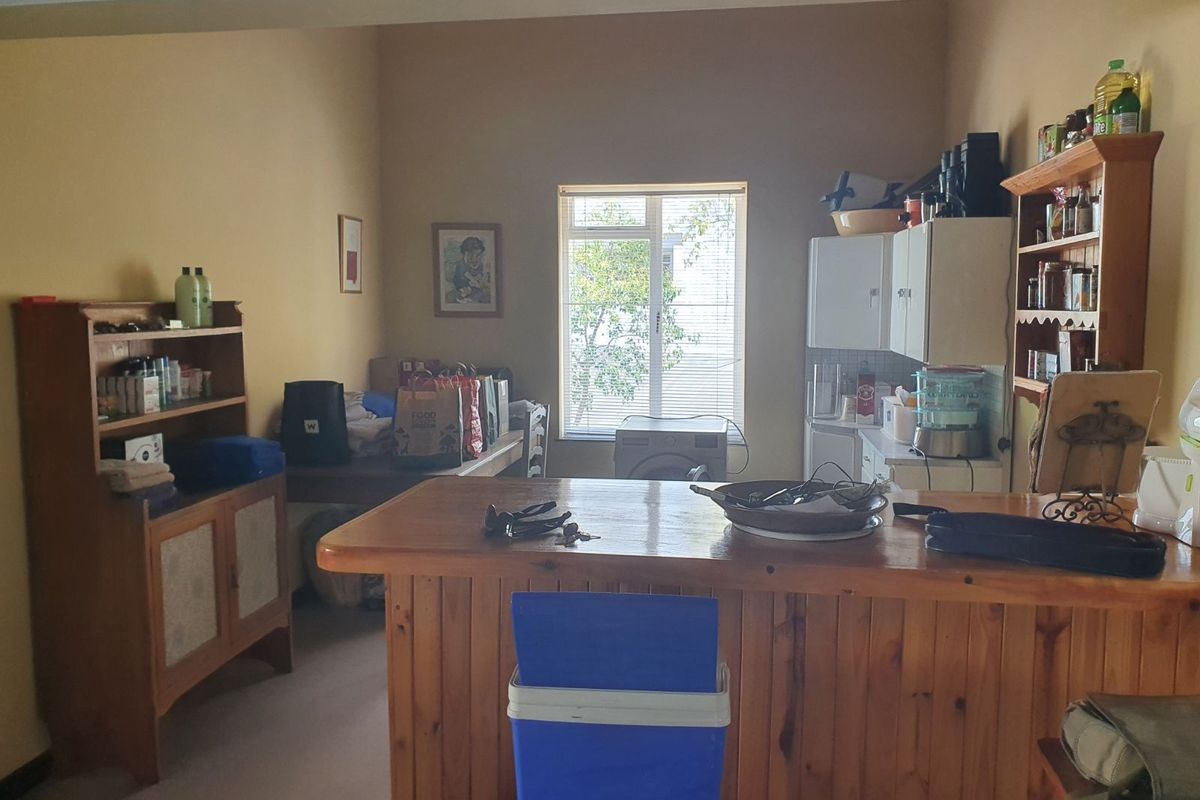A functional kitchen area featuring a timber breakfast bar, built-in cabinetry, and natural light from a window.