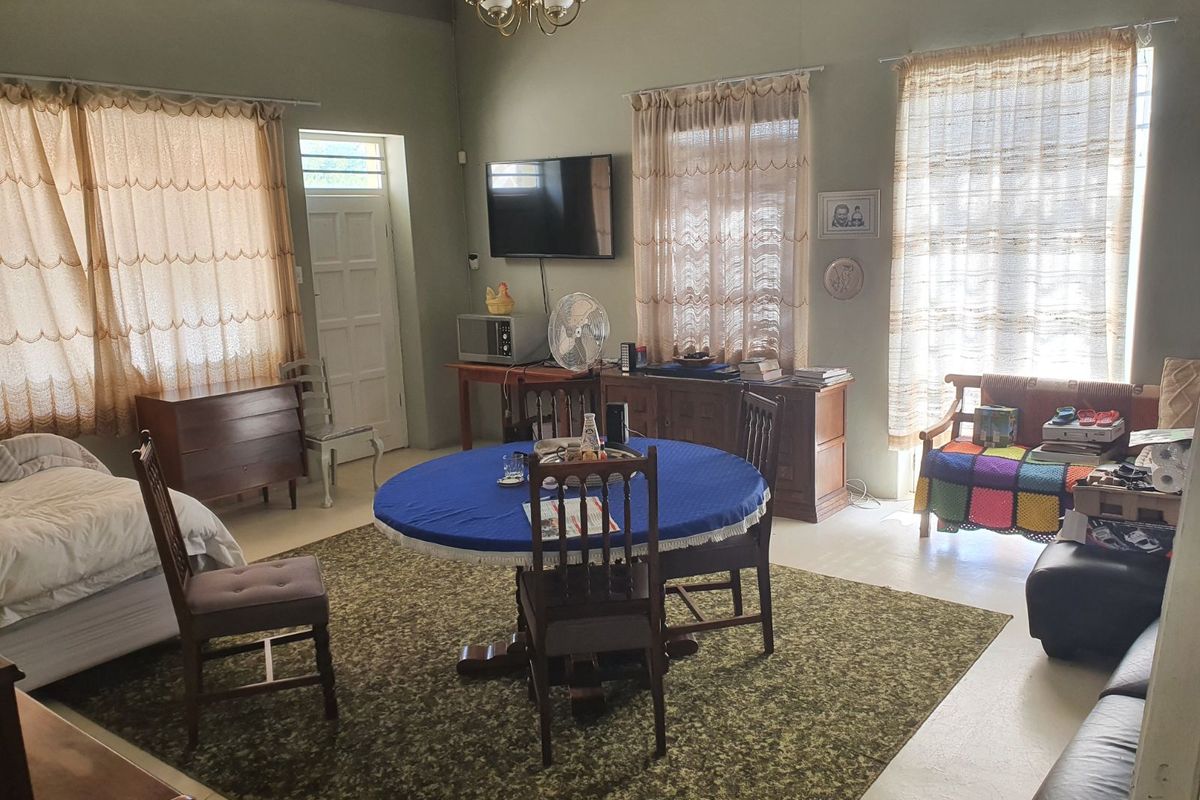 A spacious living area featuring high ceilings, a central chandelier, and multiple windows allowing natural light, suitable for a versatile open-plan layout.