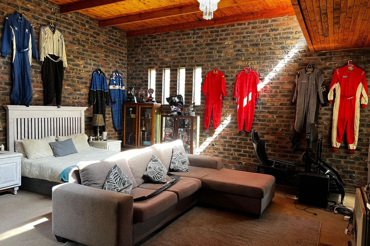 Spacious bedroom featuring exposed brick walls, high timber-beamed ceilings, and vertical slit windows, creating a unique industrial-style living space.