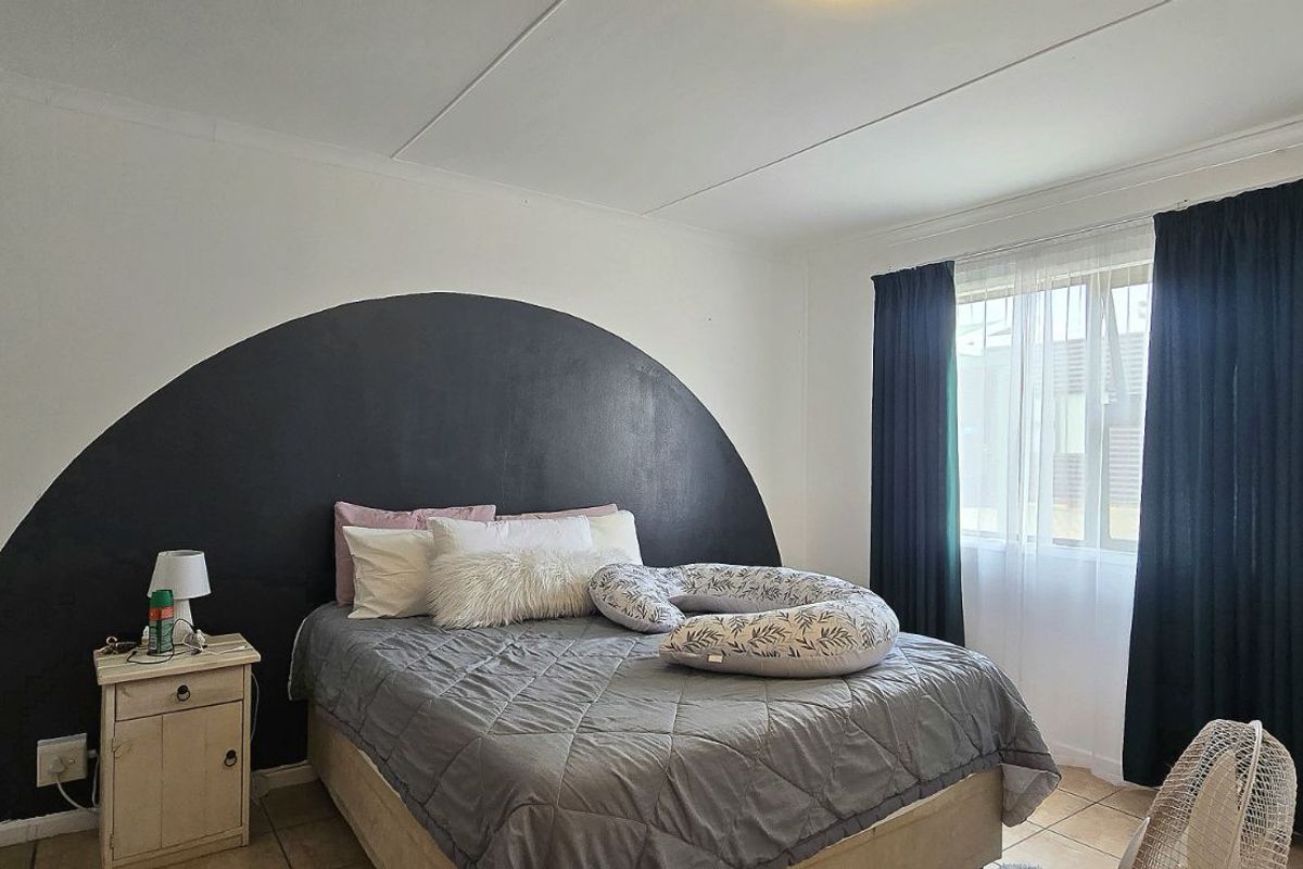 A bedroom featuring tiled flooring, built-in cupboards, and a decorative painted arch feature wall.