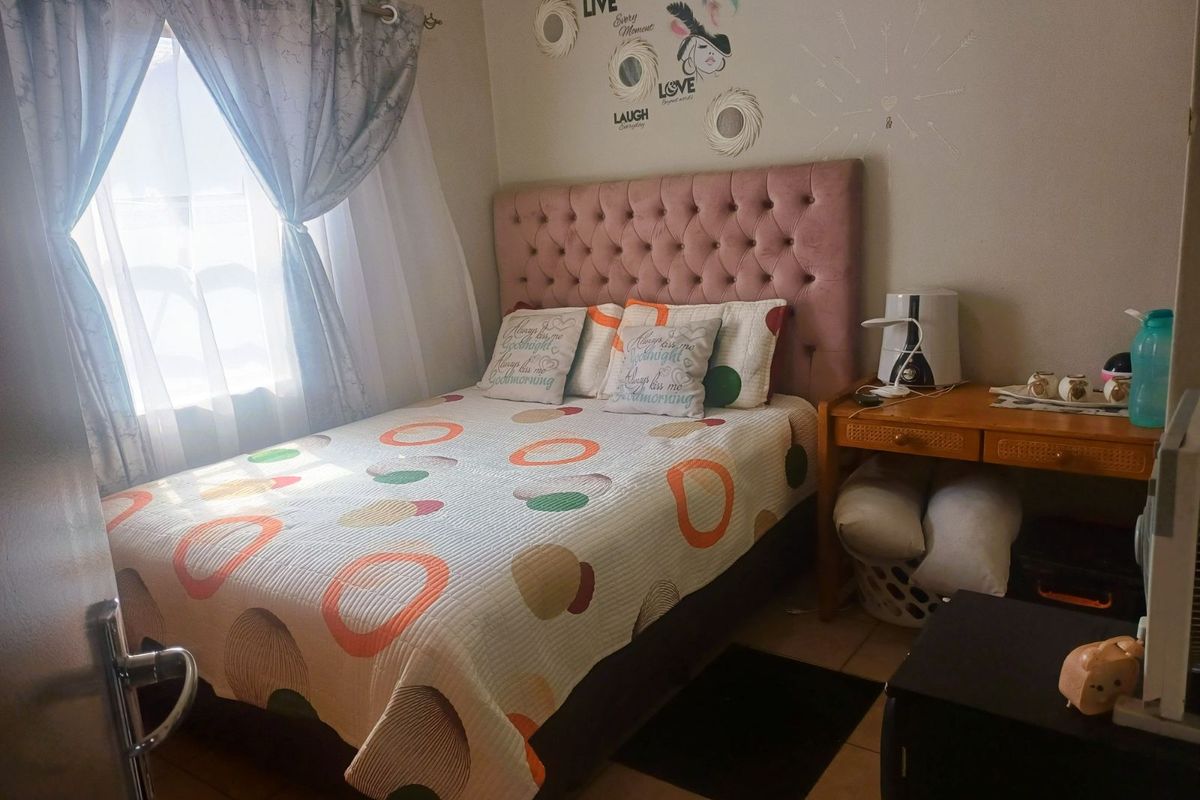 A cozy bedroom featuring tiled flooring and a window with curtains, providing a functional and comfortable sleeping space.