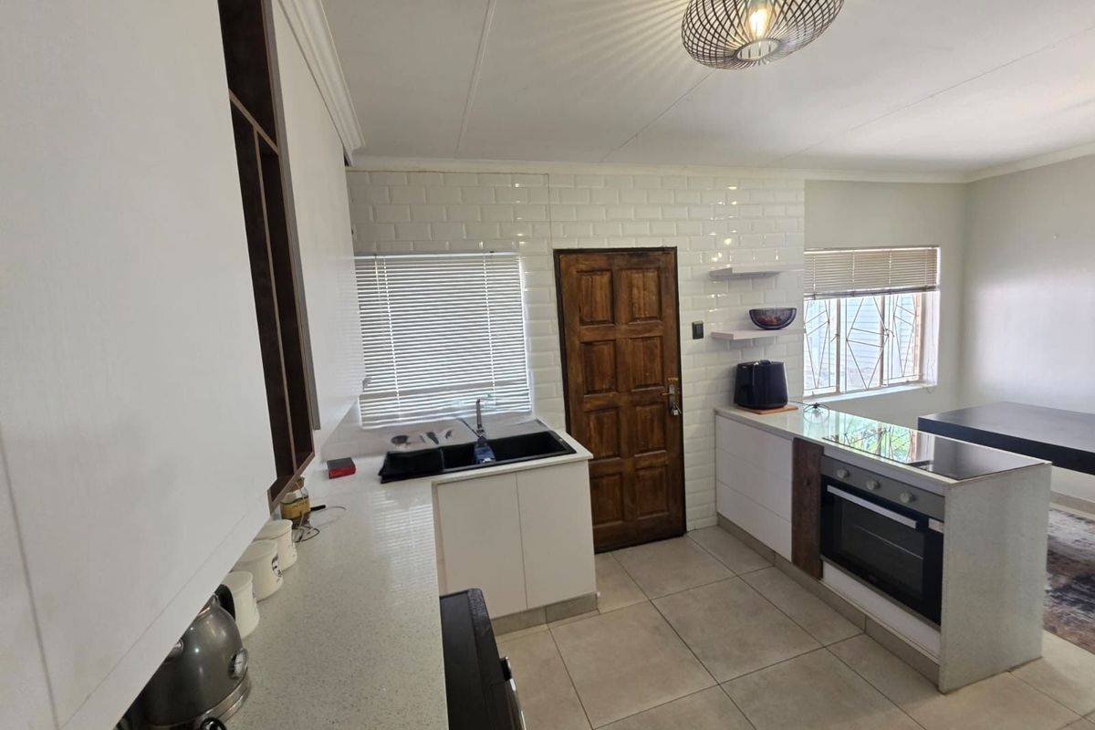 Modern kitchen featuring white cabinetry, stone countertops, built-in oven, hob, and subway tile backsplash with direct access to an exterior door.