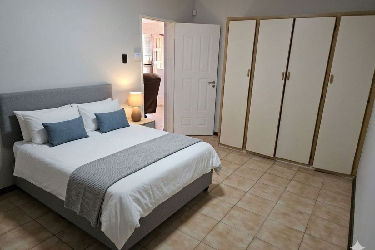 A well-maintained bedroom featuring built-in wardrobes, tiled flooring, and neutral wall finishes, offering a clean and functional living space.