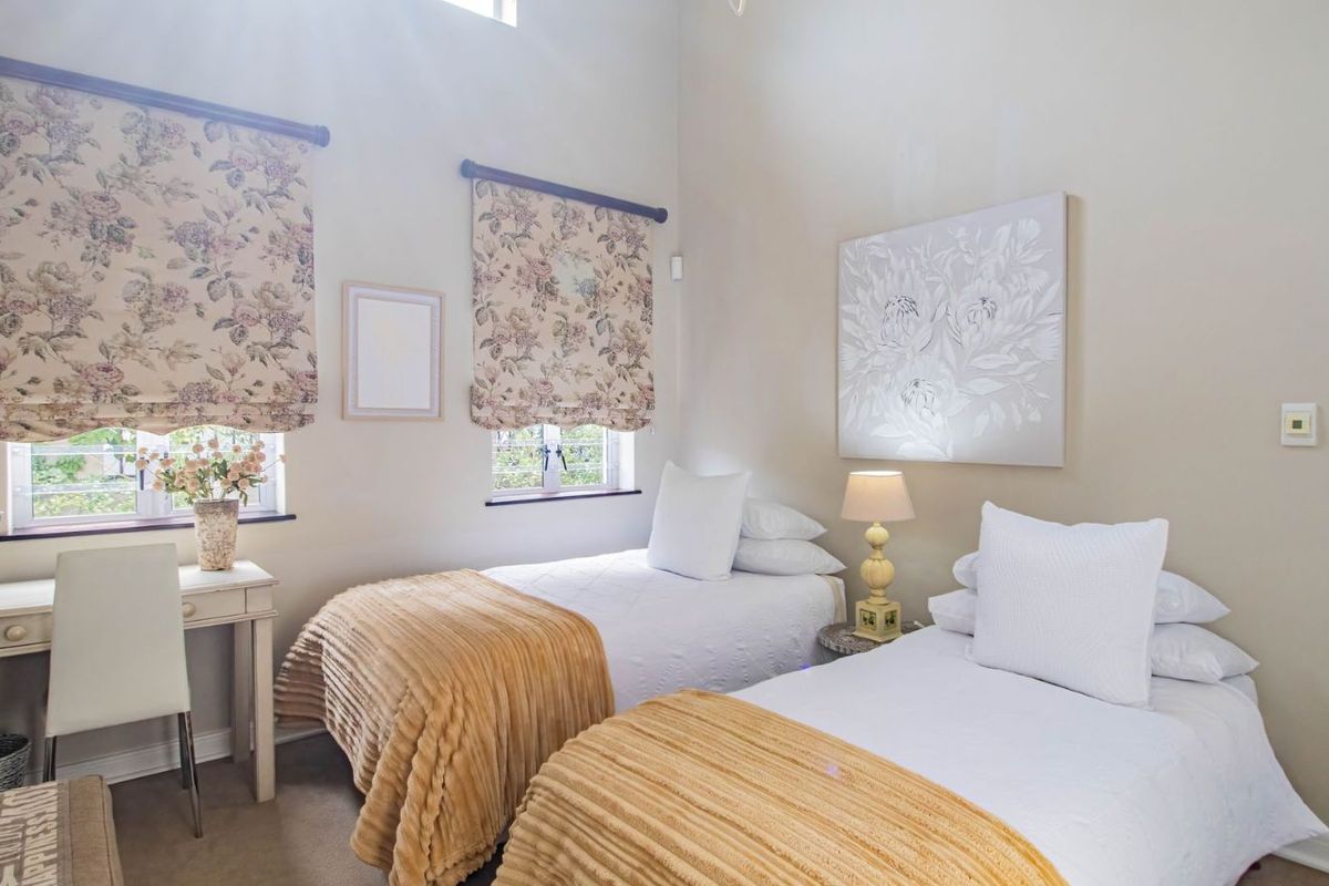 A bright bedroom featuring high ceilings, dual windows with roman blinds, and neutral wall finishes.