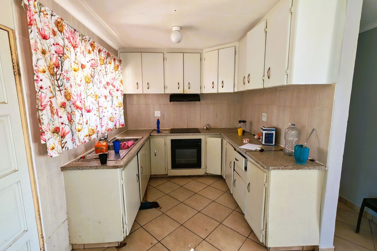 A functional U-shaped kitchen featuring built-in cabinetry, a fitted oven and hob, and tiled splashbacks, offering a practical layout for renovation.
