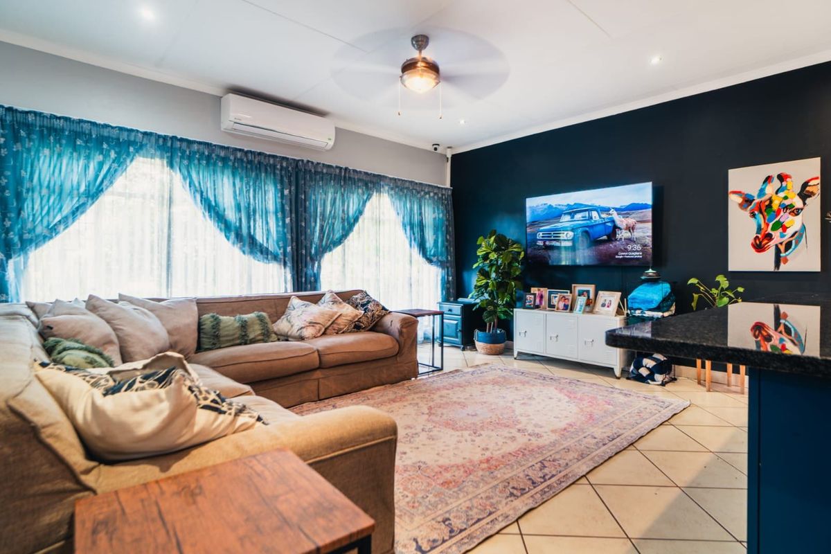 A comfortable living room featuring a ceiling fan, wall-mounted air conditioning unit, and tiled flooring, creating a functional and inviting space.