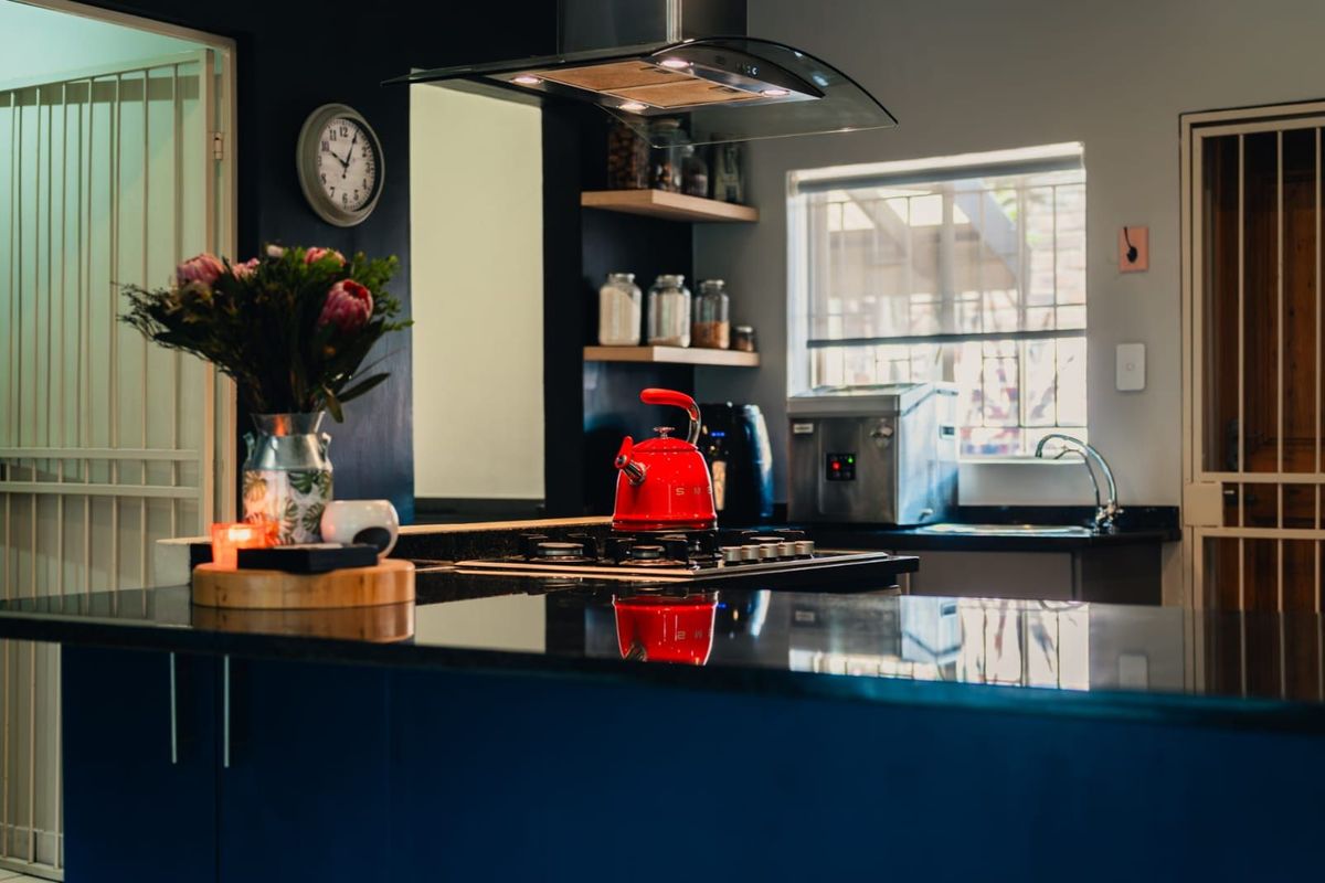Modern kitchen featuring dark cabinetry, granite countertops, a built-in gas hob, and a stainless steel extractor fan.