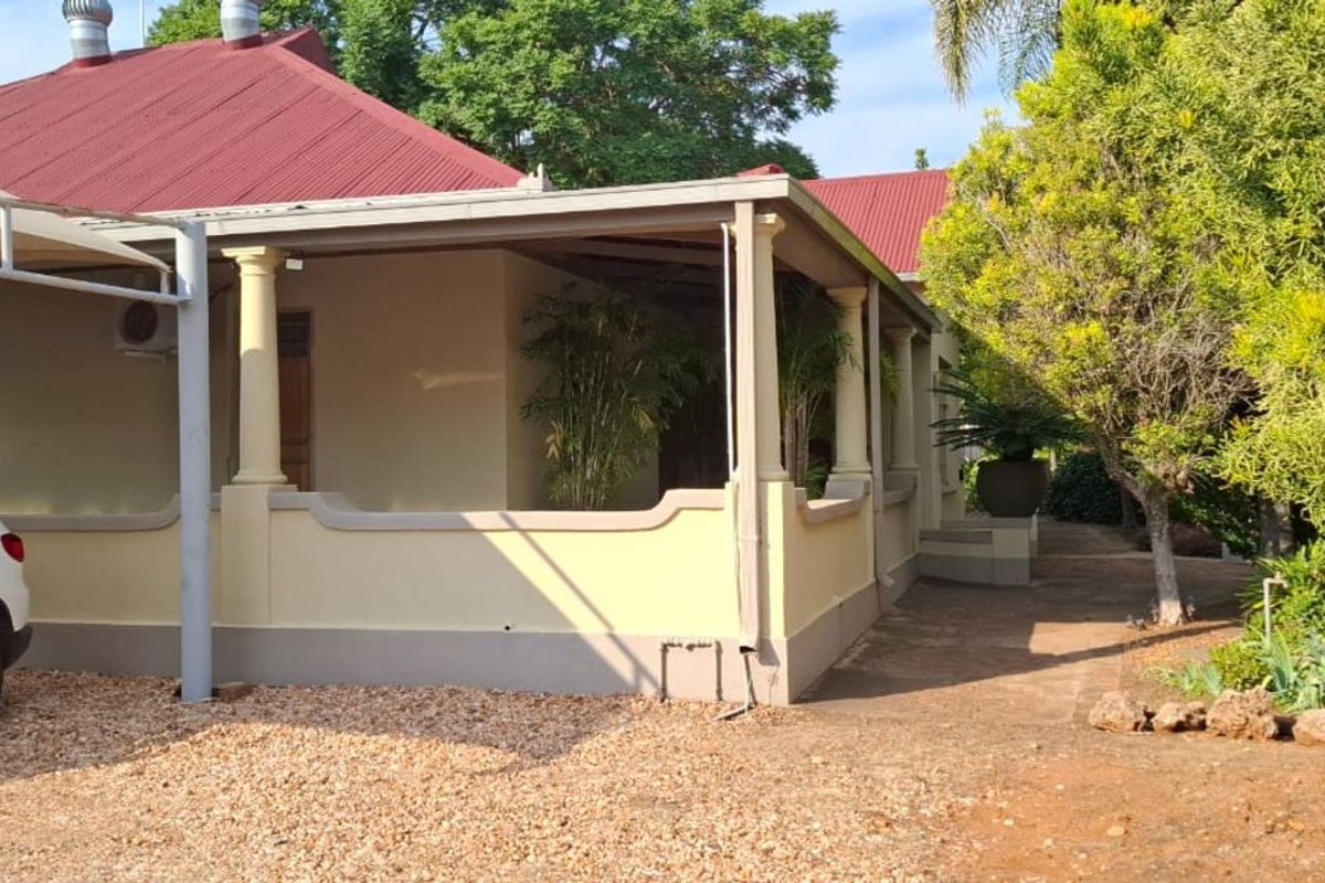 A view of the office building exterior featuring a covered patio area, metal roofing, and a gravel driveway.