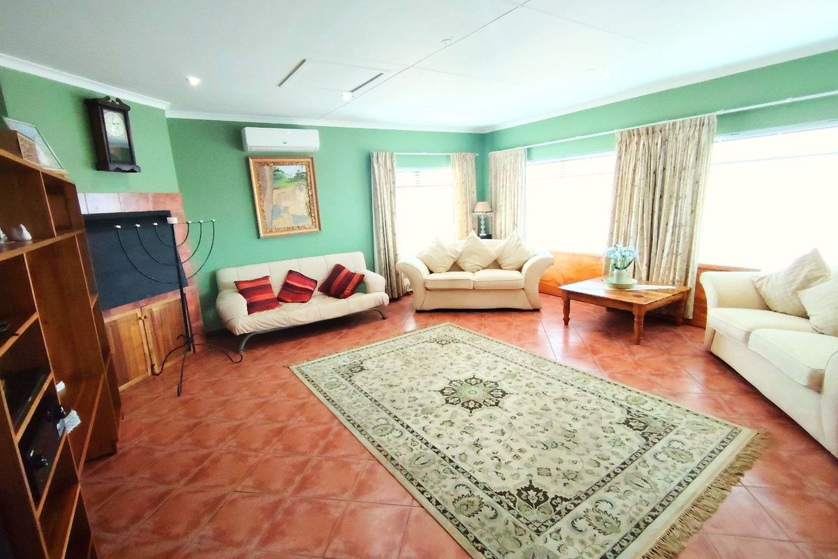 Spacious living room featuring terracotta floor tiles, a built-in fireplace, and a wall-mounted air conditioning unit.