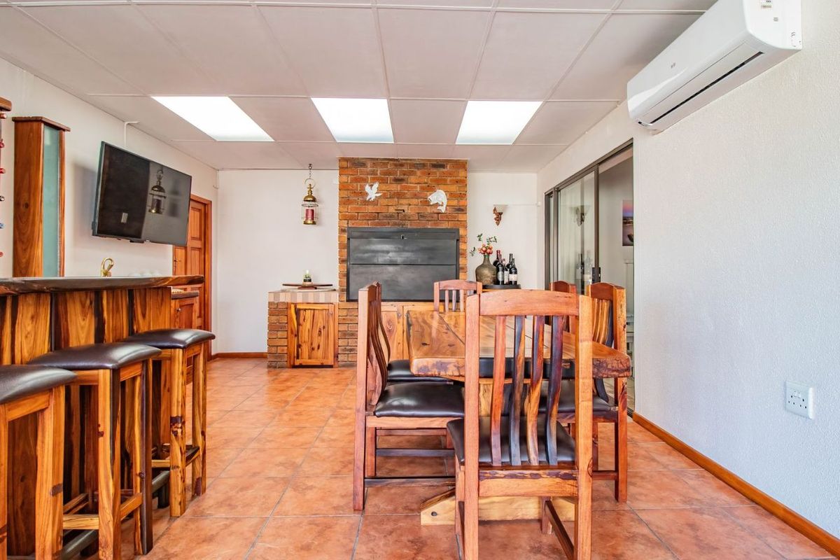 Spacious entertainment area featuring a built-in brick fireplace, bar counter, and wall-mounted air conditioning unit, finished with terracotta-style floor tiles.