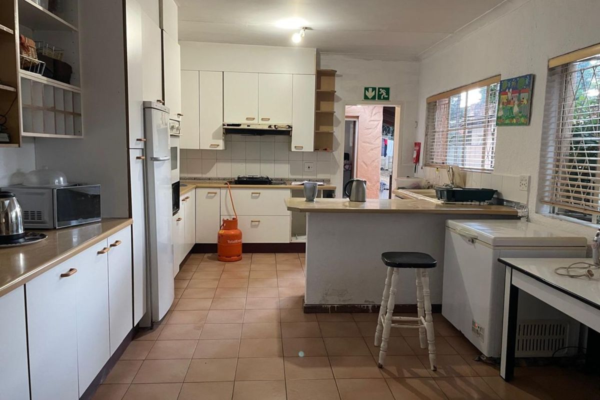 Functional kitchen featuring white cabinetry, tiled flooring, a breakfast bar, and integrated cooking appliances, offering a practical layout for daily meal preparation.
