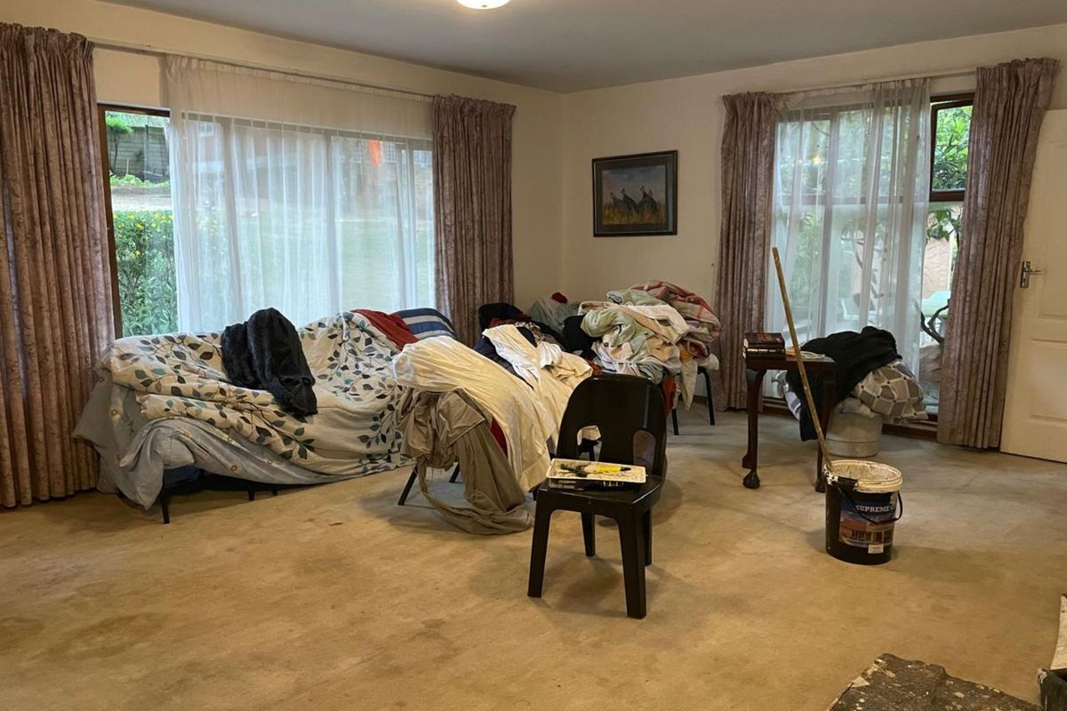 A spacious living room featuring large windows that provide natural light and access to the garden area.