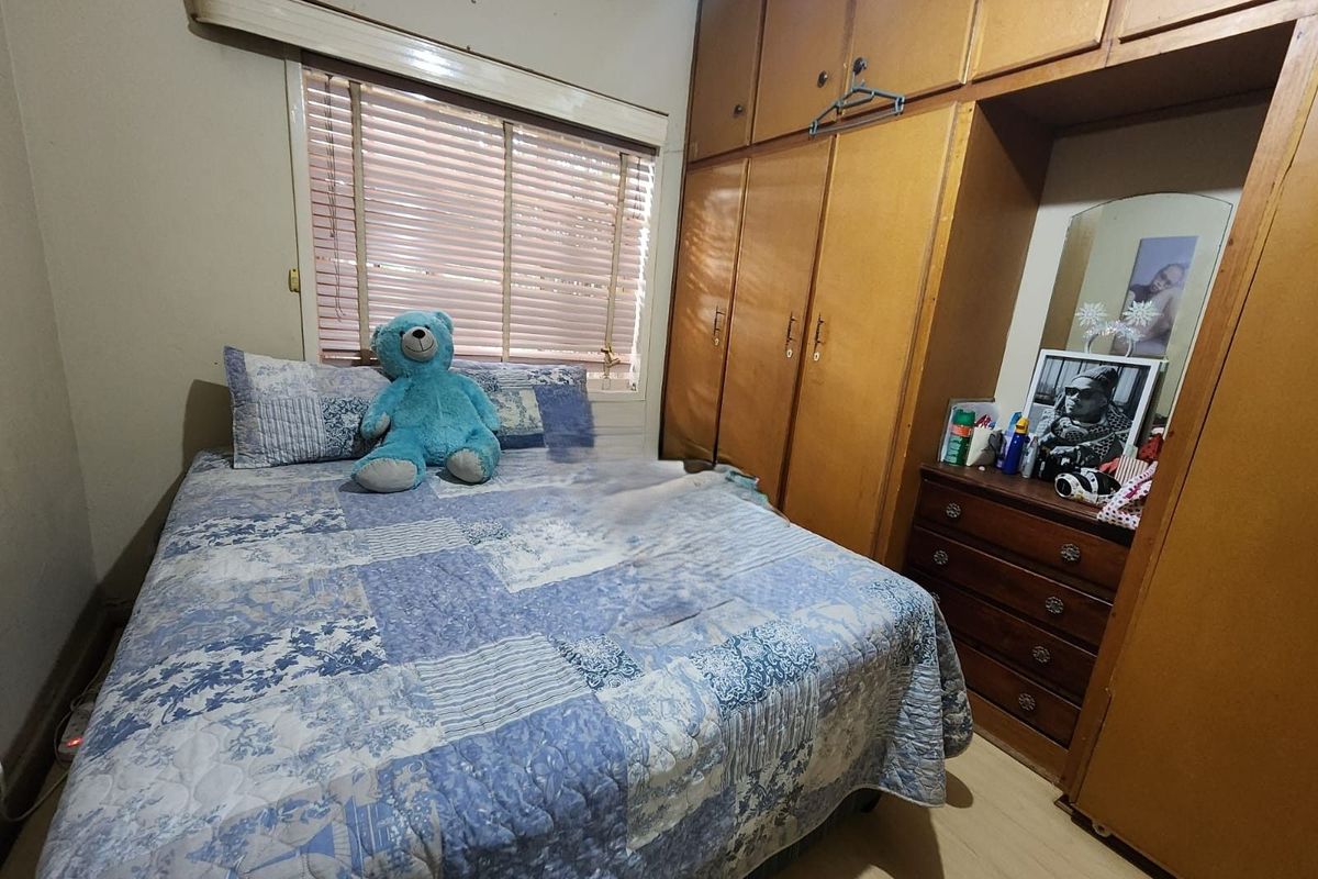 A bedroom featuring built-in wooden cabinetry and a window with fitted blinds, offering a functional space with potential for cosmetic updates.