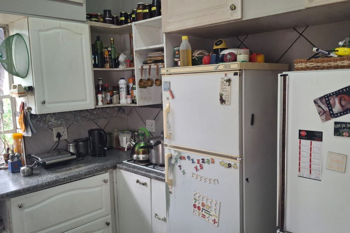 A compact kitchen featuring white cabinetry, granite-look countertops, and tiled splashbacks, offering a functional layout with integrated storage space.