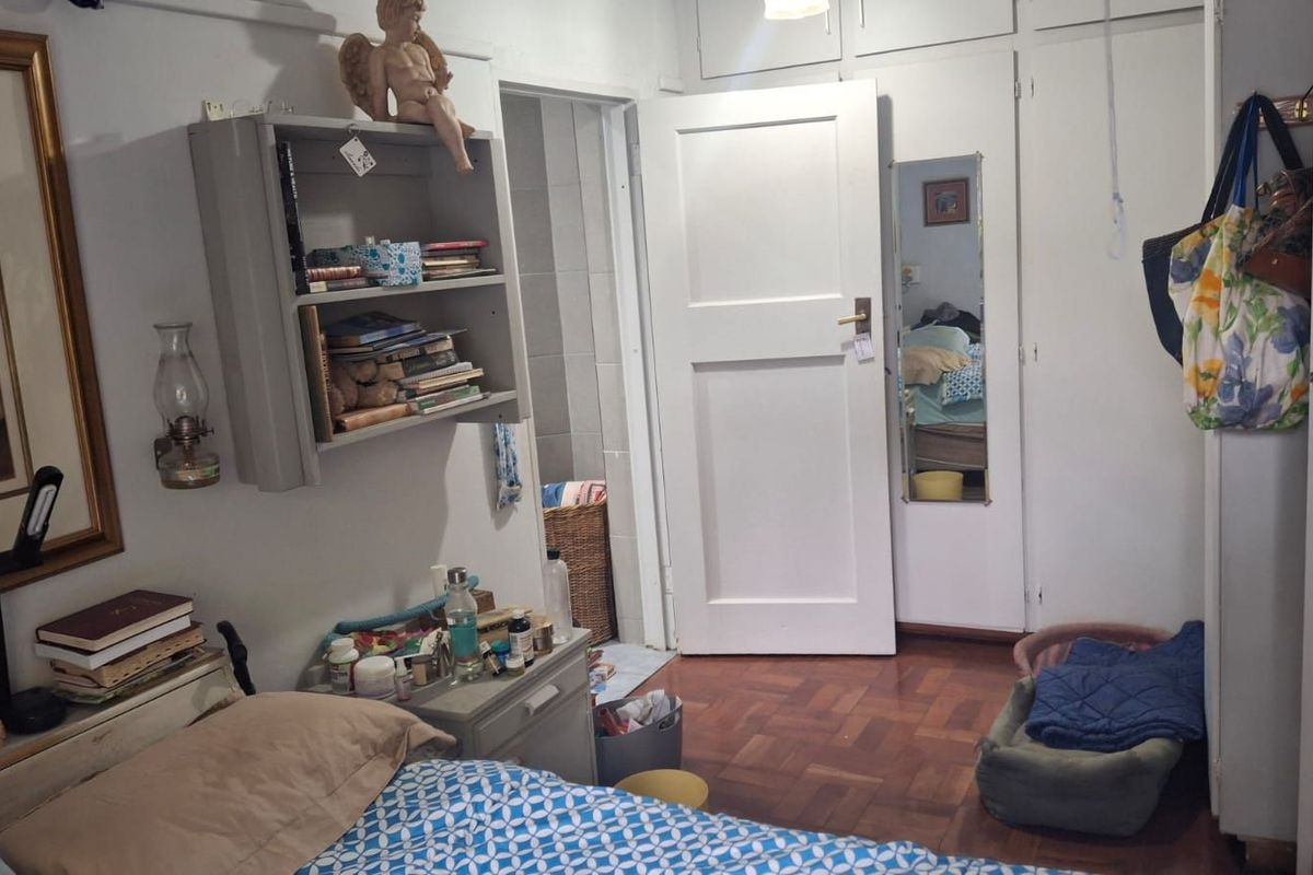 A bedroom featuring parquet flooring, built-in cupboards, and direct access to an adjoining bathroom.