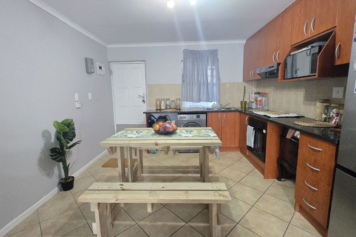 A functional kitchen featuring wood-finish cabinetry, tiled flooring, a built-in oven, and a tiled backsplash, providing a practical layout for daily meal preparation.