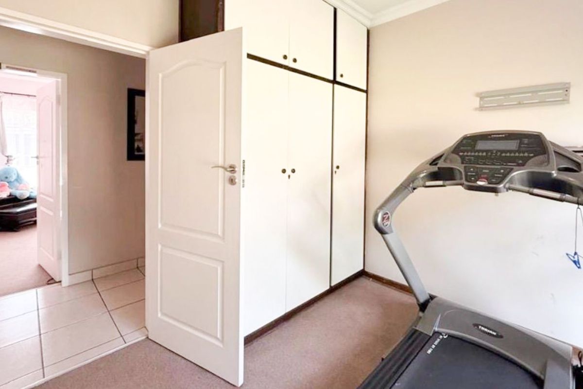 A bedroom featuring built-in floor-to-ceiling cabinetry and carpeted flooring, with an adjacent hallway visible through the doorway.