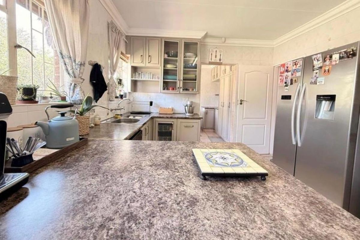 A functional kitchen featuring laminate countertops, ample cabinetry, and a connected scullery area, providing a practical layout for daily meal preparation.